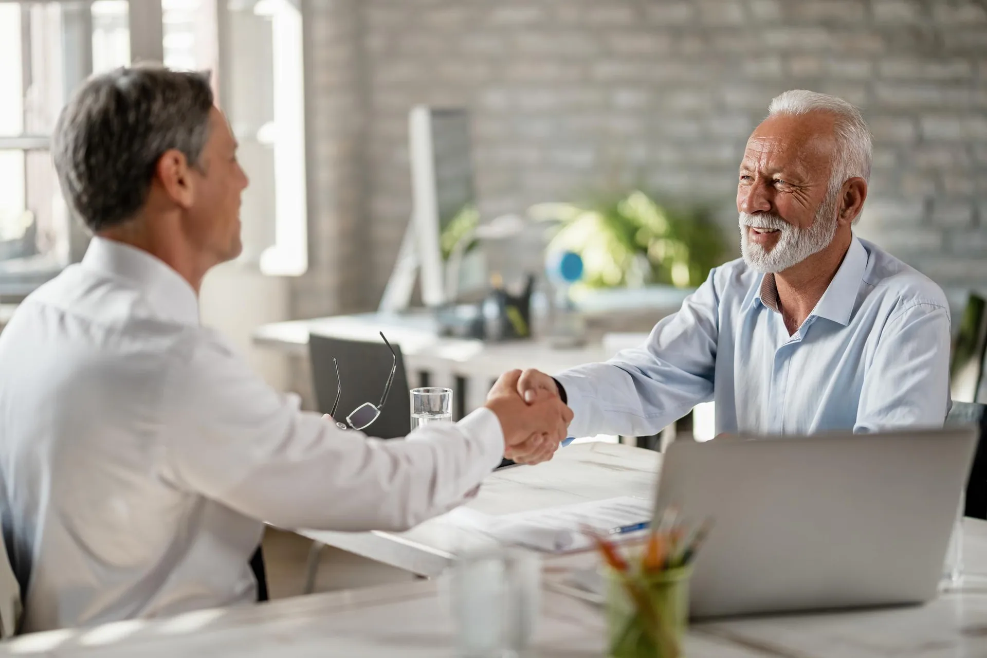 Member shaking hands with a financial advisor across a desk